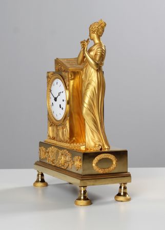 Orologio francese Impero placcato oro con raffigurazione di una dama che suona il flauto