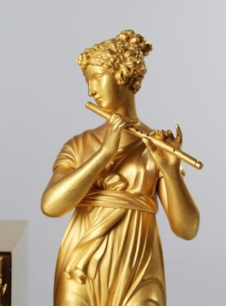 Orologio francese Impero placcato oro con raffigurazione di una dama che suona il flauto